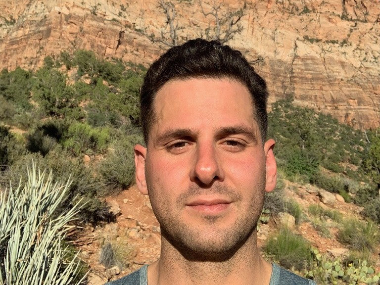 Jon, co-founder of Desert Drip, in front of a red-rock cliff under a blue sky